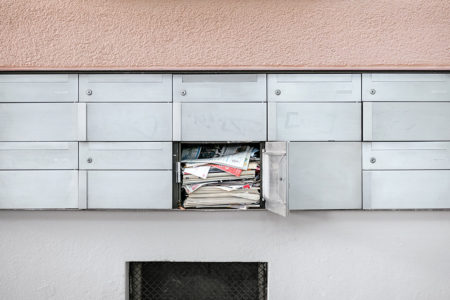 A bank of apartment mailboxes filled with mail