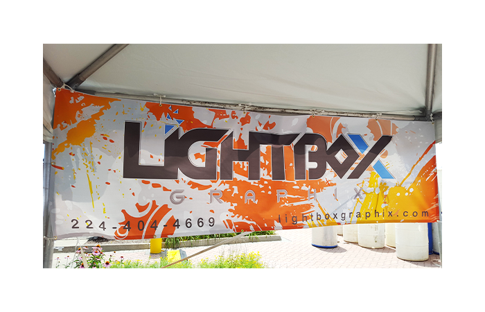 Vinyl banner printed by United GMG, hemmed and tied through its corner grommets to an event tent frame outdoors