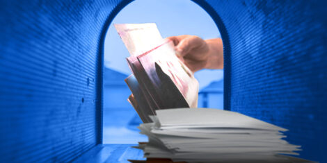 A hand dropping mail into a blue mailbox