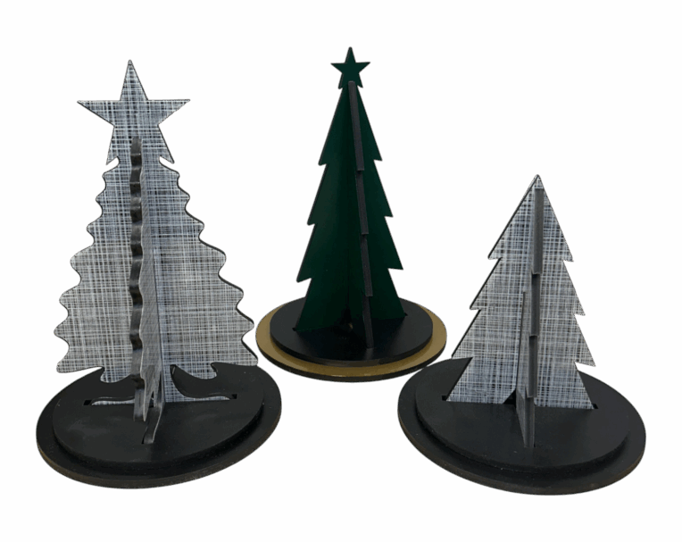 Set of three tabletop holiday tree displays with custom die-cut shapes and printed textures on round bases for seasonal decoration