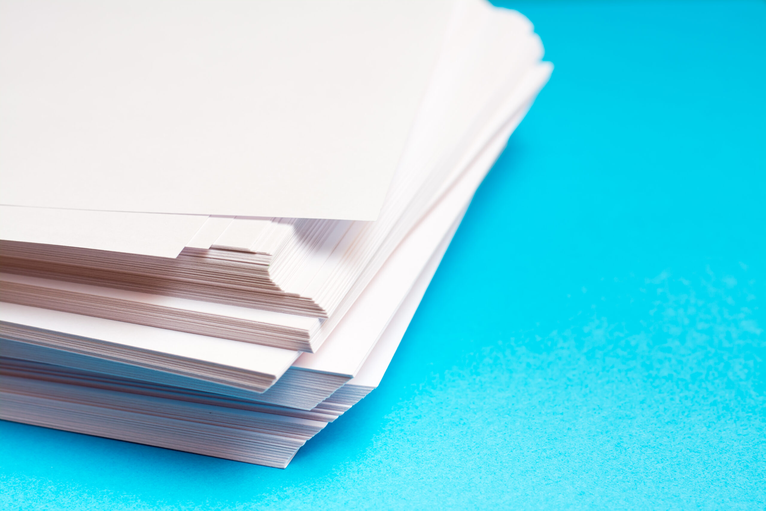 A stack of clean white paper on a table on a blue background. Bl