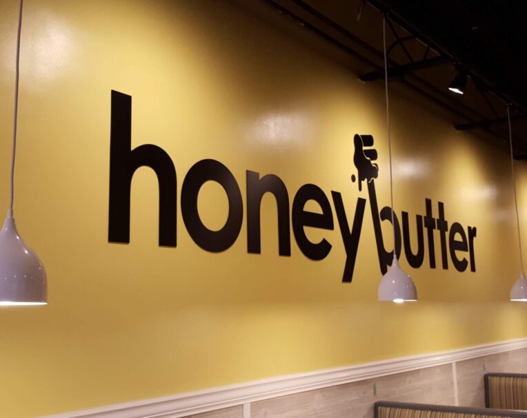 Interior wall sign for Honey Butter featuring bold vinyl lettering applied to a painted surface for branded décor