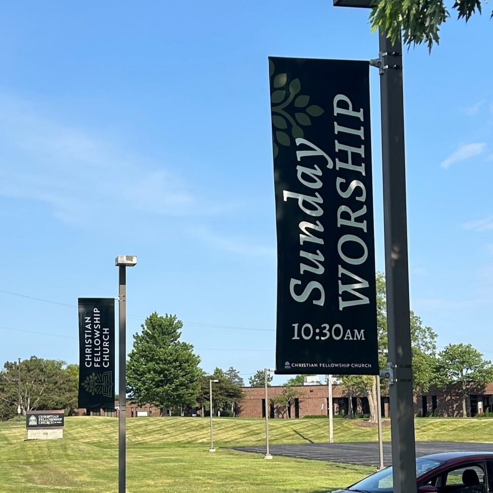 260775 Pole Banners Custom printed outdoor pole banners for Christian Fellowship Church displaying Sunday Worship at 10:30AM, installed along the entrance driveway.