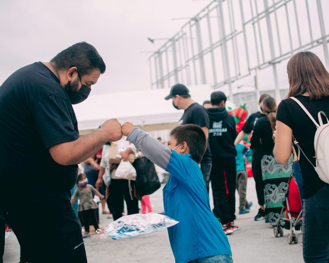 A volunteer greeting a child at a community distribution event